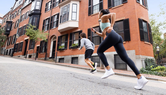 Joggers Running Uphill On City Street