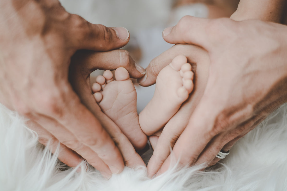 close up of mothers hands around infant feet in the shape of a heart