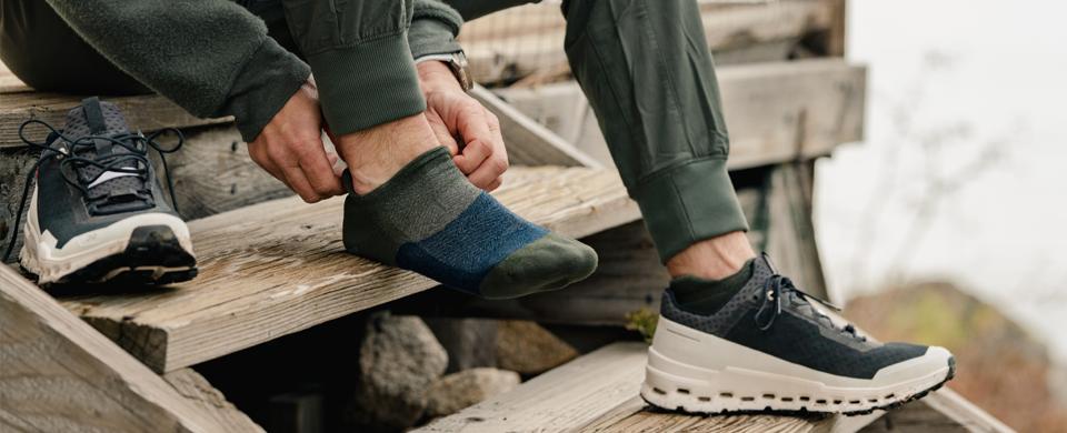 A guy putting on Merino 10 Wool Socks for men 