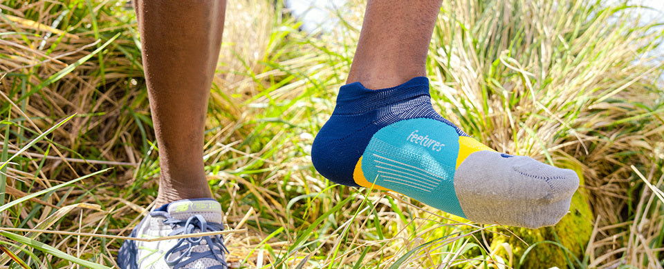 Woman walking through grass in Feetures light-cushion socks
